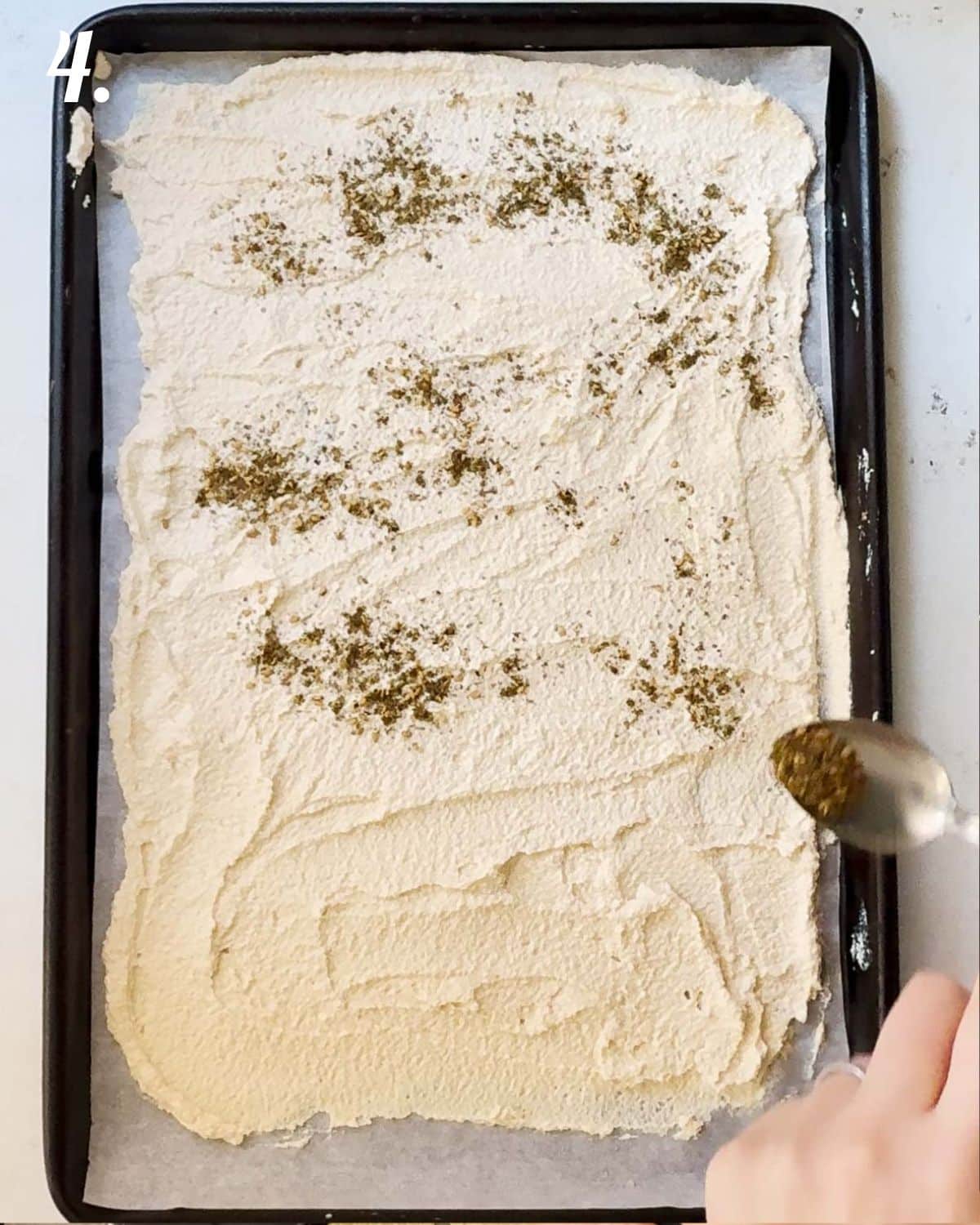 Sprinkling the seasoning over the tofu crackers before baking.