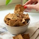A bowl of tofu crispy crackers with a few spilled next to the bowl.