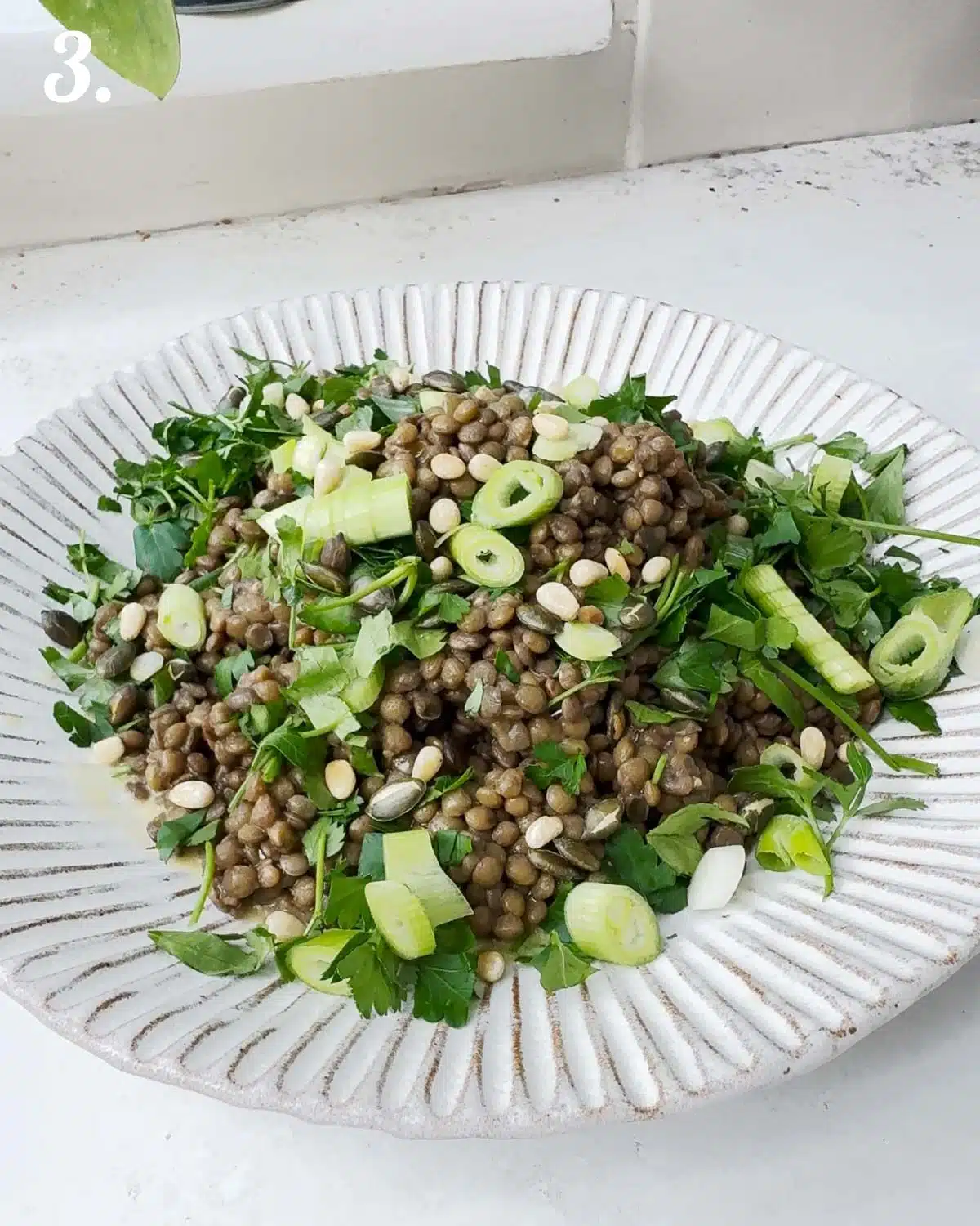 Cooked lentils with herbs and spring onions on top ready to add cherry tomatoes.