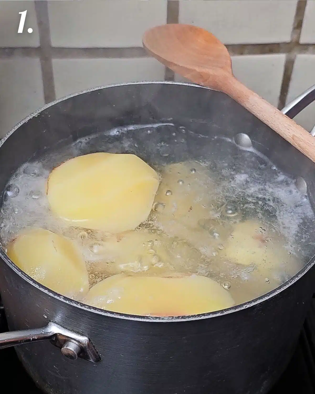 Boiling the whole potatoes in a pan.