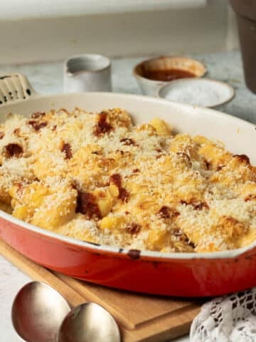 A pan of baked butternut squash and gnocchi with a cheesy harissa sauce and crunchy breadcrumb topping.