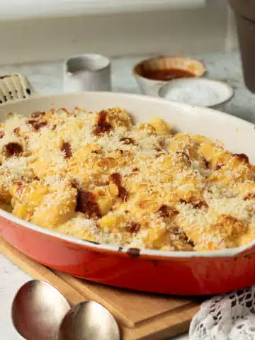 A pan of baked butternut squash and gnocchi with a cheesy harissa sauce and crunchy breadcrumb topping.