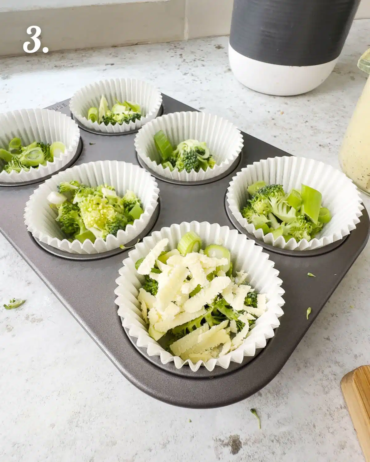 Building the egg bites by starting off with addding the additional ingredients into a muffin pan.