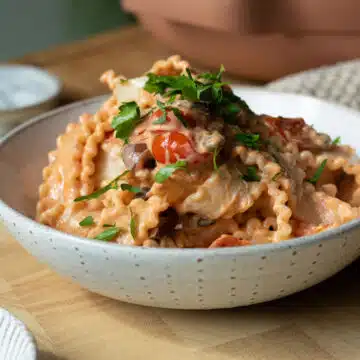 A bowl of creamy tomato puttanesca with some chopped parsley on top.