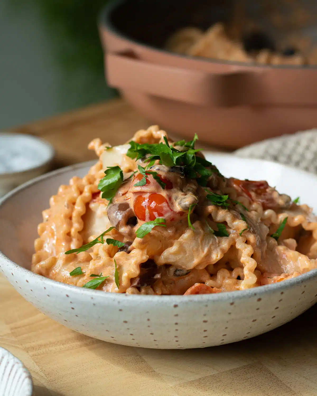 A bowl of creamy tomato puttanesca with some chopped parsley on top.