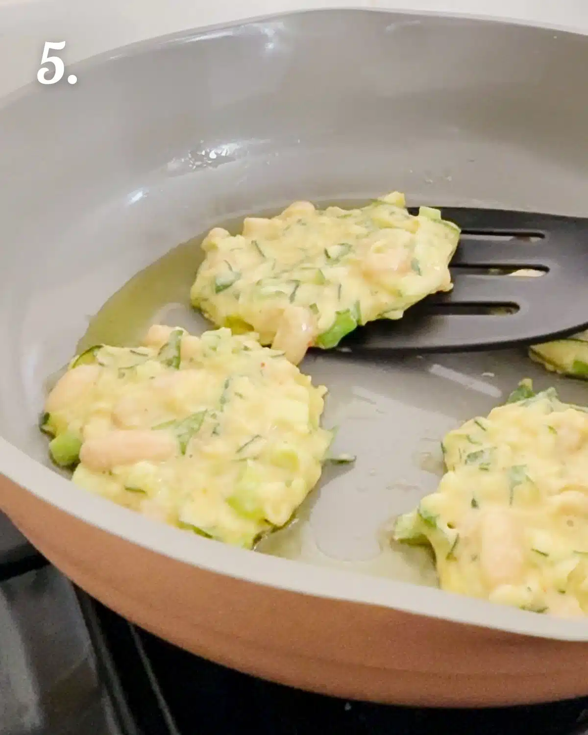 Pan frying the zucchini white bean fritters to be crispy.