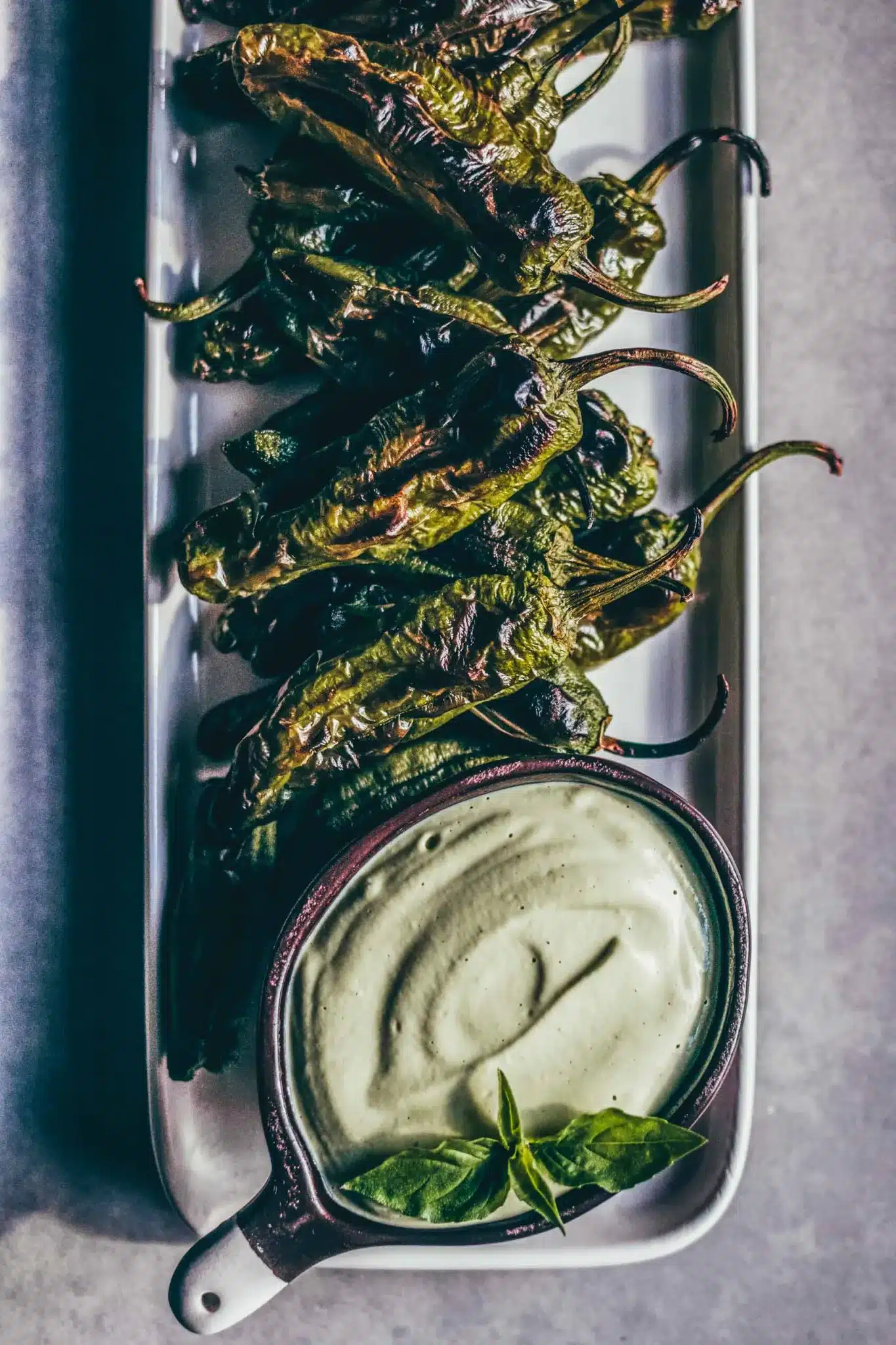 Blistered Shishito peppers with lemon basil cashew cream on a platter