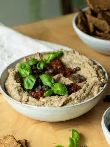 A bowl of lentil hummus with chopped sundried tomatoes over the top.