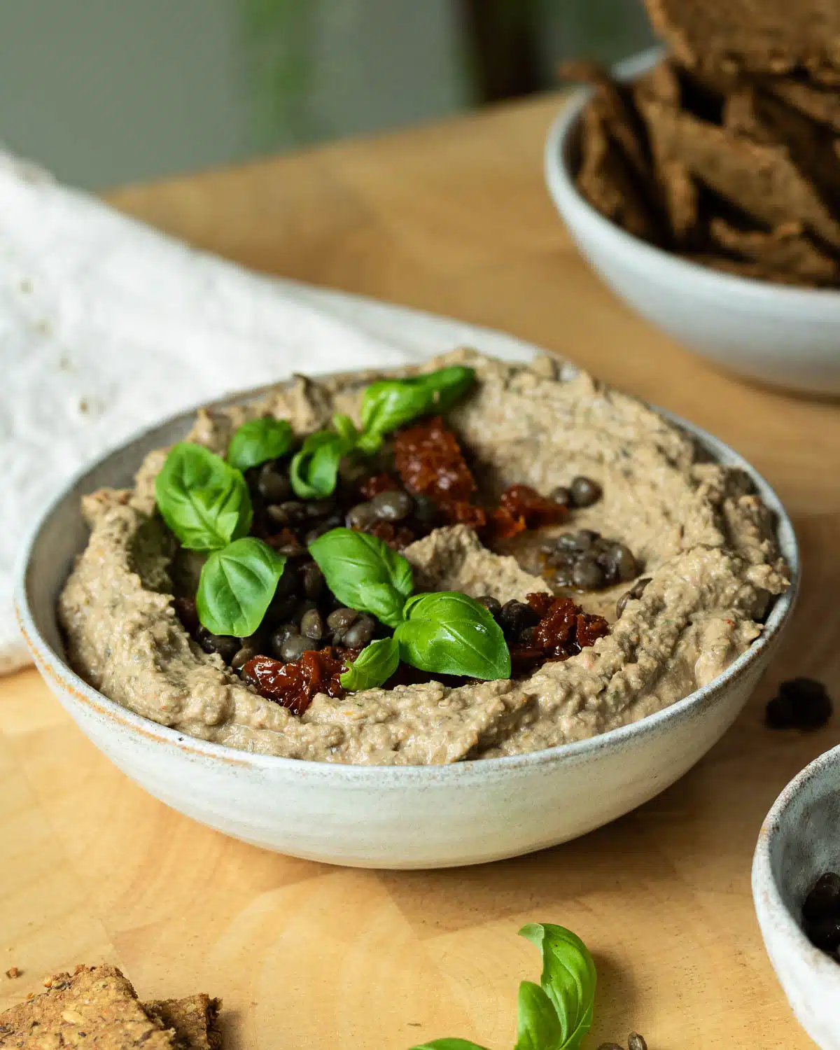 A bowl of lentil hummus with chopped sundried tomatoes over the top.