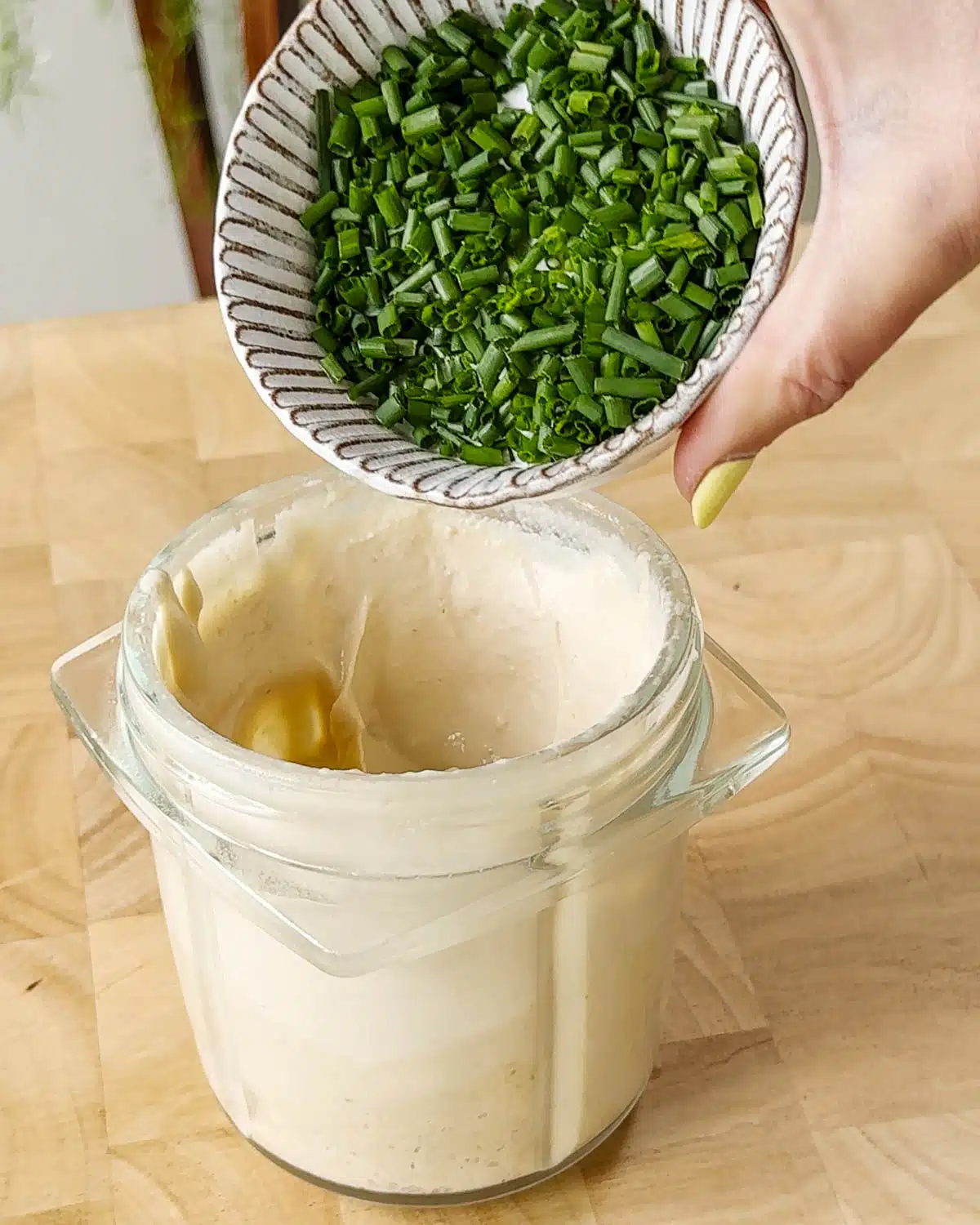 Adding the chopped chives to the dip and leaving to infuse their flavor before serving.
