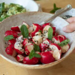 A bowl of smashed radish salad ready to eat. There is a fork picking up a piece of radish.