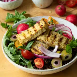 A bowl of salad with tofu halloumi on top.