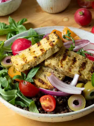A bowl of salad with tofu halloumi on top.