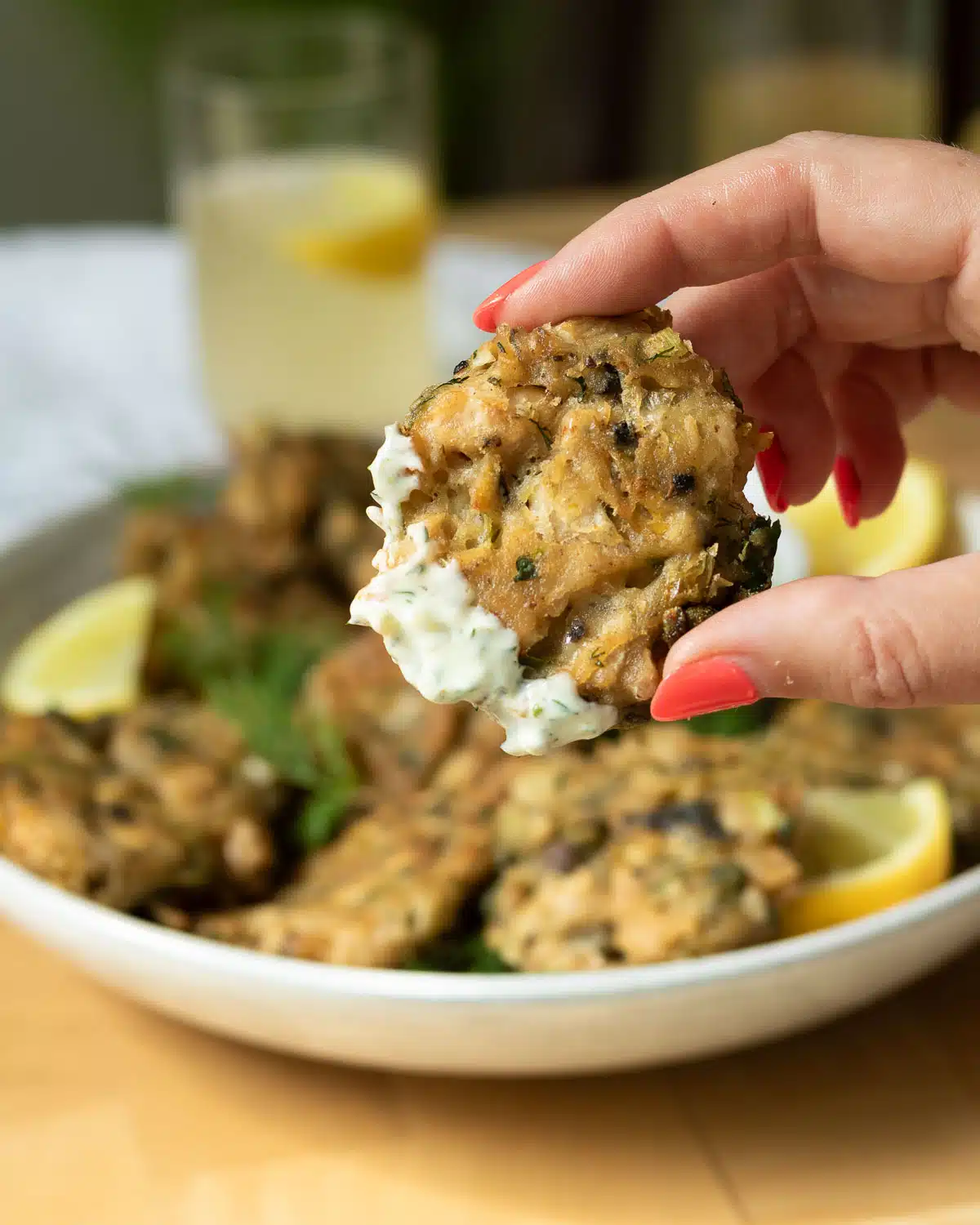 A vegan crab cake that has been dipped in tartar sauce being held up before eating it.
