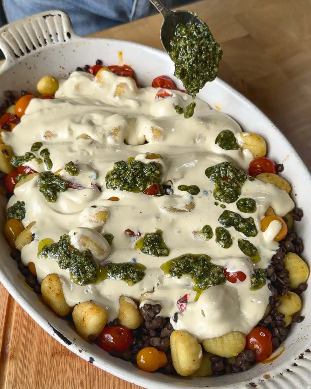 Dot the tofu cheese mixture with homemade pesto and return to the oven to continue to bake.