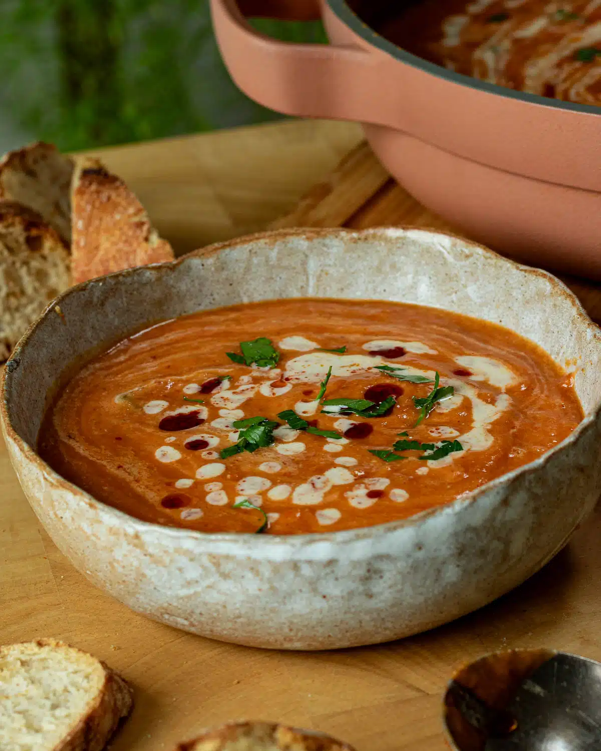 A bowl of roasted sweet potato and red lentil soup with a tahini harissa drizzle on top in a bowl ready to serve.
