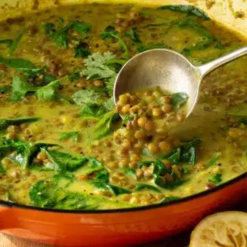 A pan of lentil soup in a creamy spiced coconut broth. There are coriander leaves sprinkled over the top.