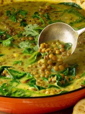 A pan of lentil soup in a creamy spiced coconut broth. There are coriander leaves sprinkled over the top.