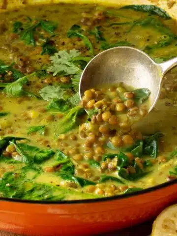 A pan of lentil soup in a creamy spiced coconut broth. There are coriander leaves sprinkled over the top.